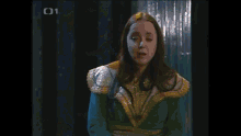 a woman in a yellow dress stands in front of a blue curtain with the letters c1 on the bottom