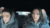 two women are sitting in the back seat of a car looking out the window