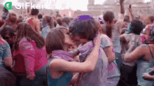 a man and woman are kissing in front of a crowd of people covered in colored powder .