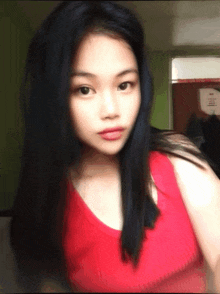 a girl in a red tank top looks at the camera