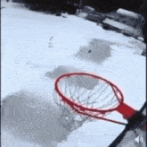 a person is playing basketball in the snow with a red rim