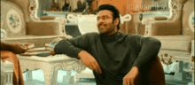 a man is sitting on a couch with his arms crossed and smiling in a living room .
