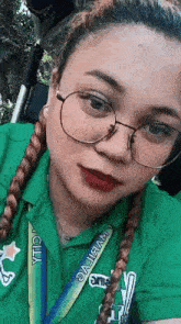 a woman wearing glasses and a green polo shirt is taking a selfie .