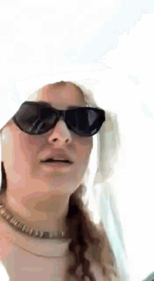 a woman wearing sunglasses and a hat is making a face .