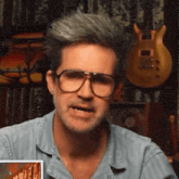 a man wearing glasses and a blue shirt is talking