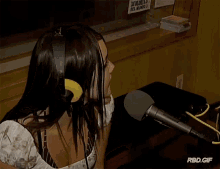 a woman wearing headphones sits in front of a microphone with a sign on the wall that says los mejores del mundo on it