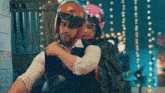 a man is carrying a woman on his back who is wearing a pink helmet .