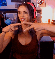 a woman wearing headphones and a tank top is smiling and pointing
