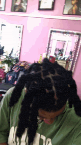a woman with dreadlocks is wearing a green shirt with the letter a on the front