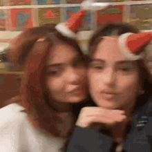 a couple of girls wearing santa hats on their heads .