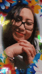 a woman wearing glasses and a white shirt is surrounded by colorful flowers