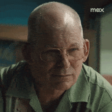 a man adjusts his glasses in front of a screen that says max