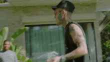 a man with a tattoo on his arm is standing in front of a window .