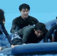 a man in a wetsuit is crawling on a blue raft