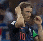 a soccer player wearing a headband is adjusting his hair while standing on the field .