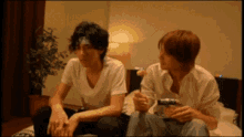 a man with a bandage on his head sits next to another man sitting on a bed
