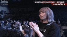 a woman applauds in front of a crowd at cinderella tournament 2025