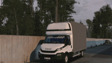 a white iveco truck is parked next to a wooden fence