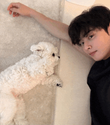 a man laying on a bed with a small white dog