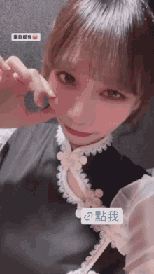 a girl wearing a black dress with white lace sleeves is making a heart shape with her hand