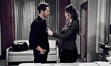 a man and a woman are standing next to each other in a hospital room and looking at each other .