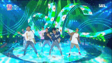 a group of people dancing on a stage with a sbs logo on the bottom