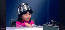 a little girl wearing a strainer on her head
