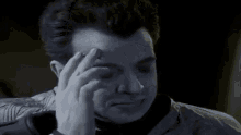 a man is holding his hand to his forehead and looking at something .