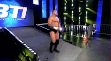a wrestler in a ring with the word bti on the screen behind him