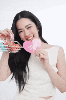 a woman is holding a pink heart that says catchy doll