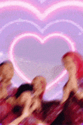 a group of girls are dancing in front of a pink heart shaped light .