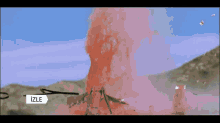 a soldier is kneeling down with a machine gun in front of a mountain with the word izle on the bottom right