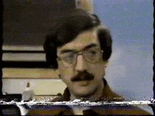 a man with glasses and a mustache is shown on a screen