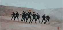 a group of men in suits are dancing on a dirt hill .