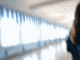 a blurry picture of a person walking down a hallway with blue curtains
