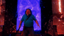 a man with a beard and a blue shirt is standing in front of a blue and red light .