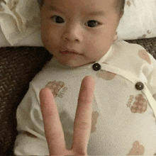 a baby is laying on a couch and making a peace sign with his hands