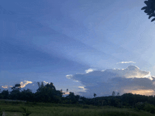 the sun is shining through the clouds over a grassy field