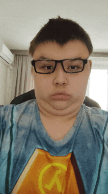 a young man wearing glasses and a blue shirt with a yellow s on it