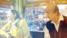 a man and a woman are looking out of a window with a bus in the background that says dalip