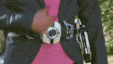 a woman in a suit and pink shirt is wearing a belt with a red buckle .