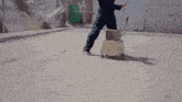 a man is pushing a cart with a mop and a box on it .