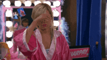 a woman in a pink robe covering her eyes in front of a chair that says harpay