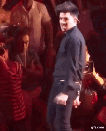 a man in a black shirt is dancing in front of a crowd of people .