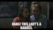 two women are sitting next to each other with the words dang this lady 's a badass