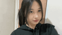 a young girl in a black hoodie is taking a selfie in front of a door .