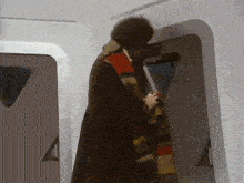 a man wearing a scarf and a coat is standing in a doorway