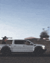 a man holding a rifle in the back of a white raptor truck