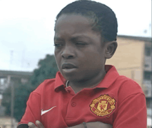 a young boy wearing a red shirt with the word manchester on it