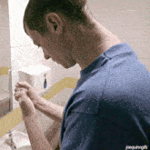a man in a blue shirt is washing his hands